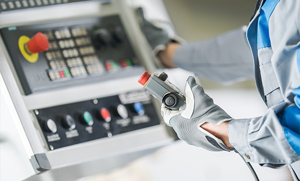 person operating a control panel using a machine with multiple colored buttons focused on precise industrial operations involving six essential controls
