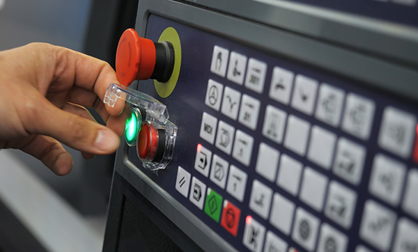 hand pressing a green button on a control panel with several buttons and icons connected to machinery and equipment 7 essential functions for operation
