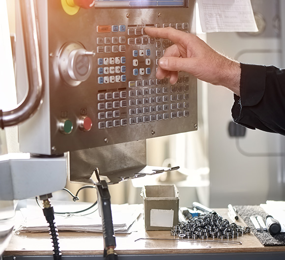 operator using CNC machine control panel to program settings for precision manufacturing process 3D machining