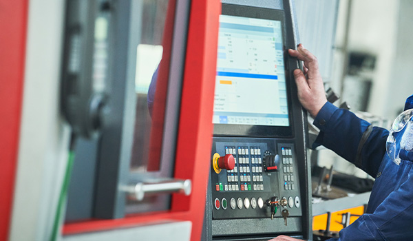 man operating a modern machine control panel in a manufacturing setting showcasing advanced technology and efficiency in production processes related to essential 5 manufacturing steps