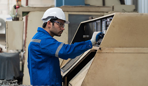 worker in safety gear operating machinery in factory setting focused on task related to machine settings and industrial processes 4 important steps for safety